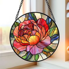 a stained glass flower hanging from a chain on a window sill in front of a window