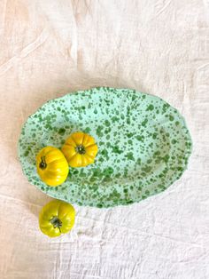 two small yellow and green peppers sitting on top of a green plate next to each other