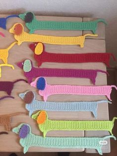 several crocheted dogs are displayed on a wooden board with shoes and toys in the background