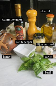 an assortment of spices and condiments on a white tablecloth with basil, olive oil, balsamc vinegar, salt & pepper