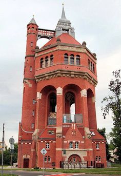 a tall red brick building with a clock on the top and two towers above it