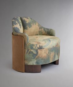 an upholstered chair sitting on top of a wooden base