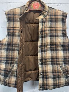 Vintage 1980s brown Tartan Plaid reversible puffer vest by Peter Hankins Inc.  The other side is brown nylon.  Quilted with nylon fill.  Both sides have pockets.  Excellent vintage condition.  No noted flaws.  Tagged size XL.  Please use measurements to decide if the fit is right for you.  Laid flat and measured.  Shoulder to shoulder - 19 inches  Chest (armpit to armpit) - 24 inches  Waist - 23 inches  Length - 24 inches Sleeveless Brown Outerwear For Outdoor, Brown Sleeveless Vest For Cold Weather, Vintage Winter Vest Outerwear, Hunting Vest Outerwear Sleeveless, Hunting Sleeveless Vest Outerwear, Sleeveless Hunting Vest Outerwear, Vintage Sleeveless Winter Outerwear, Vintage Outdoor Vest For Fall, Vintage Vest For Outdoor Fall Activities