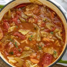 a large pot filled with lots of food on top of a wooden table next to a napkin