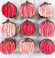 cupcakes decorated with pink frosting and green leaves on a marble counter top