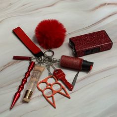 the contents of a purse are laid out on a white sheet with red accessories and lipstick