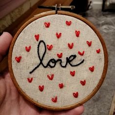 someone is holding up a hand embroidered love sign