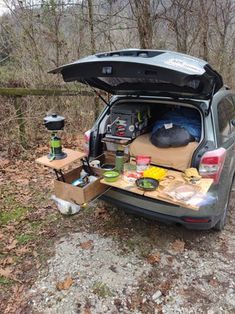 the back end of a car with its trunk open and camping supplies in it's trunk