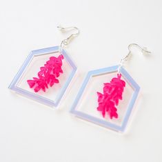 These dangle greenhouse earrings feature a delicate pink leaf inside a greenhouse. The design is perfect for someone that loves the outdoors - flowers, plants, nature or gardening - or simply enjoys beautiful things. If you're stuck for a gift for your mum or girlfriend, these earrings are sure to hit the mark. Laser cut from perspex acrylic, they hang from low nickel silver-plated hooks. The leaf is pink and the house is iridescent acrylic. All items are presented in white branded luxury gift b