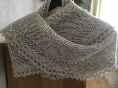 a white knitted shawl hanging from a hook