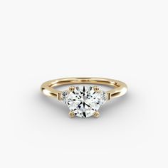 a yellow gold engagement ring with a round brilliant cut diamond in the center and two small diamonds on each side