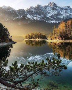 a lake surrounded by mountains with trees in the foreground