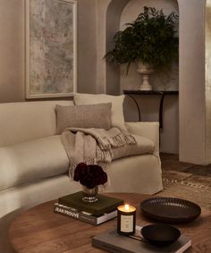 a living room with a couch, coffee table and vase on the end table in front of it