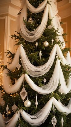 a christmas tree decorated with white ribbons and ornaments