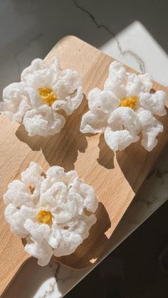 three white flowers are placed on a wooden board