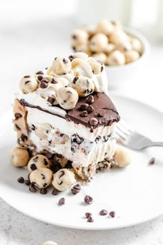 a white plate topped with a piece of cake covered in chocolate chips