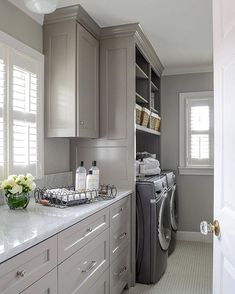 a washer and dryer are in the middle of a large kitchen with gray cabinets