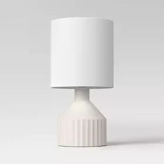 a white table lamp with a white shade on it's top and bottom part