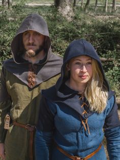 a man and woman dressed in medieval clothing standing next to each other on a path