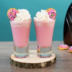 two pink drinks with sprinkles and donuts on the top are sitting next to each other