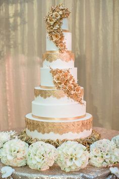 a three tiered wedding cake with white and gold flowers