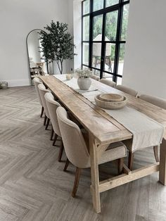 a dining room table with chairs and a bowl on top of it in front of a large window