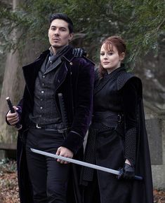 a man and woman dressed in medieval clothing holding swords while standing next to each other