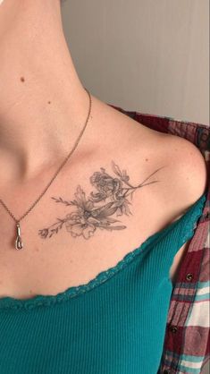 a woman with a flower tattoo on her chest is wearing a green shirt and has a silver necklace