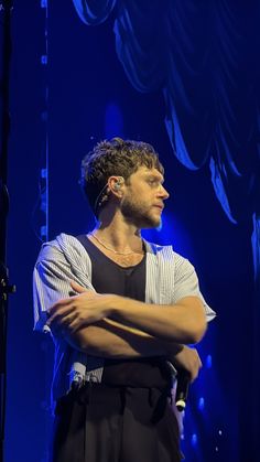 a man standing with his arms crossed on stage