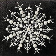 a black square with white dots and an intricate snowflake design on the center