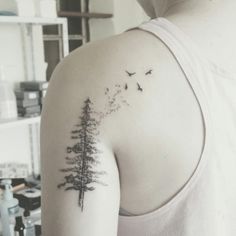 a person with a tree tattoo on their back shoulder and one bird flying in the air