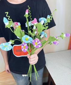 a person holding a bunch of flowers in their hand and wearing a black t - shirt