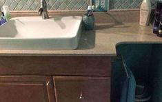 a bathroom sink sitting under a mirror next to a counter top with bottles on it