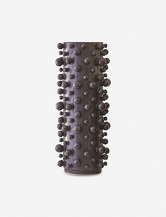 a tall vase with lots of black balls on it's sides and the bottom