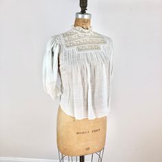 "Antique Edwardian white check cotton blouse has a lace yoke, pin tucks at the bust, and lace trimmed sleeves. The blouse has pin tuck down the length of the back, buttons for closure and a tie at the waist. Condition Overall good condition, has a stain at the back right shoulder area, tiny-small holes around the right sleeve shoulder area, a small hole near the back right pit seam, and a pink-ish stain near the shoulder. There's also a tiny hole near the back left shoulder. There's also a pink Lace Insert Blouse, Classic Cotton Blouse With Lace Trim, Lace Collar Top For Daywear In Fall, Fall Lace Top With Lace Collar For Daywear, Cotton Tops With Pintucks For Daywear, Cotton Peasant Top With Lace Trim For Daywear, Classic White Lace Top For Daywear, White Classic Lace Top For Daywear, Cotton Lace Top With Ruffles For Daywear