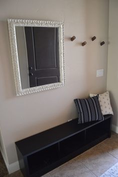 a black bench sitting under a mirror in a room