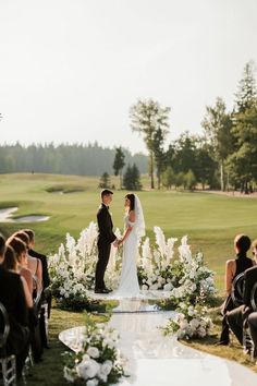 a bride and groom standing at the end of their wedding ceremony in front of a golf course