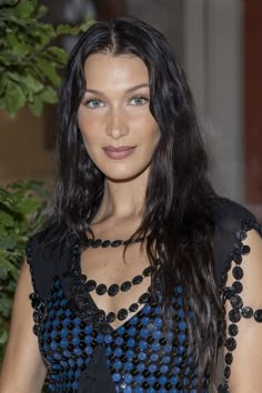 a woman with long dark hair wearing a blue and black dress