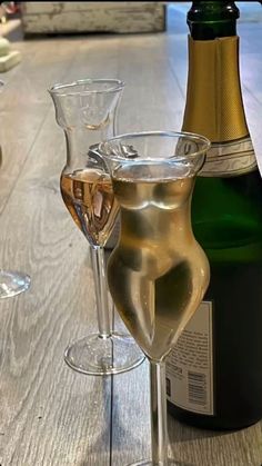 two wine glasses sitting on top of a wooden table next to a bottle of wine