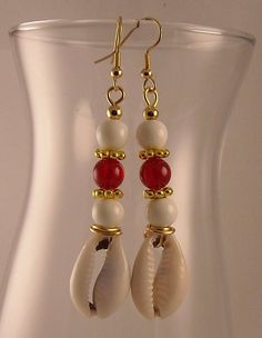 EARRINGS ON THE LEFT:  Consist of handmade natural copper ear wires and spacer beads with cream color acrylic beads and cowrie shells.  Dangles 3 1/4 inches long. EARRINGS ON THE RIGHT:  Consist of red and white glass beads with gold spacers beads and cowrie shells.  They dangle 3 inches long. The ever popular cowrie shell has many uses and meanings. It has shown up in the form of money, jewelry, and religious accessories in almost every part of the world. Found in the islands of the Indian Ocean, the cowrie shell soon gained popularity throughout much of ancient Africa. Spiritually, according to African legend, if you are attracted to cowrie shells you could be family to an ocean spirit of wealth and earth. It also represents Goddess protection which is very powerful and connected with th Bohemian Copper Wire Jewelry With Round Beads, Bohemian Beaded Earrings With Copper Wire, Bohemian Copper Wire Beaded Earrings As Gift, Red Bohemian Hoop Earrings For Beach, Bohemian Red Hoop Earrings For Beach, Beaded Copper Wire Drop Earrings, Beaded Drop Earrings With Copper Wire, Money Jewelry, Earrings Aesthetic