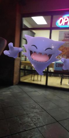 an odd looking object is in front of a store window with its mouth open and tongue out