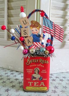 an old tea can is decorated with patriotic decorations and letters to spell out the word usa