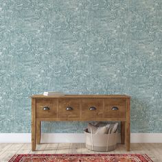 a wooden table sitting in front of a blue wall with a rug on top of it