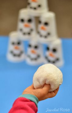 a hand holding a snowball in front of a stack of diced up snowmen