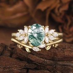 a green and white ring sitting on top of a piece of wood next to flowers