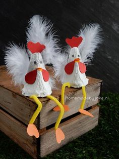 two paper mache chickens sitting on top of a wooden crate