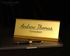 a pen sitting on top of a desk next to a business card holder that reads, andrew thomas consuliant