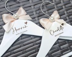 two white hangers with pink bows and name written on them, sitting next to each other