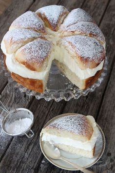 a cake sitting on top of a wooden table next to a glass bowl filled with powdered sugar