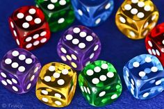 six different colored dices with white dots on them, all lined up in a circle